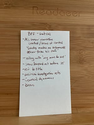 Index card with handwritten notes in copper ink, titled "BFF - initial" resting on a wooden reading stand. Full transcription in the following text.