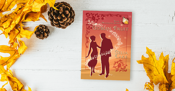 Copy of Goblin Fruit lying on a white wood desk, surrounded by golden yellow leaves and pinecorns that highlight the yellow in the cover.