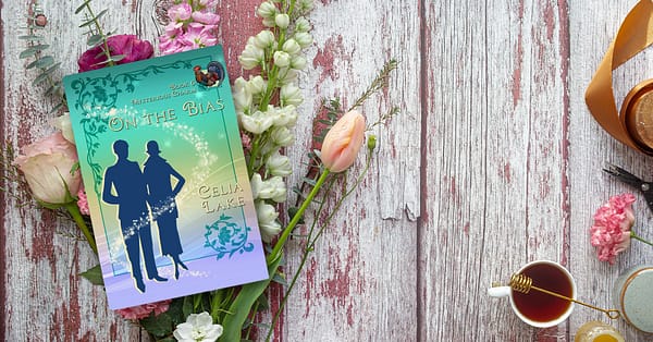 Copy of On The Bias lying on a bouquet of early summer flowers, with tea and honey nearby, in shades of pinks and pastel greens.